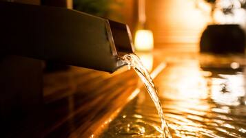 A close-up of water flowing from a faucet into a reflective surface.