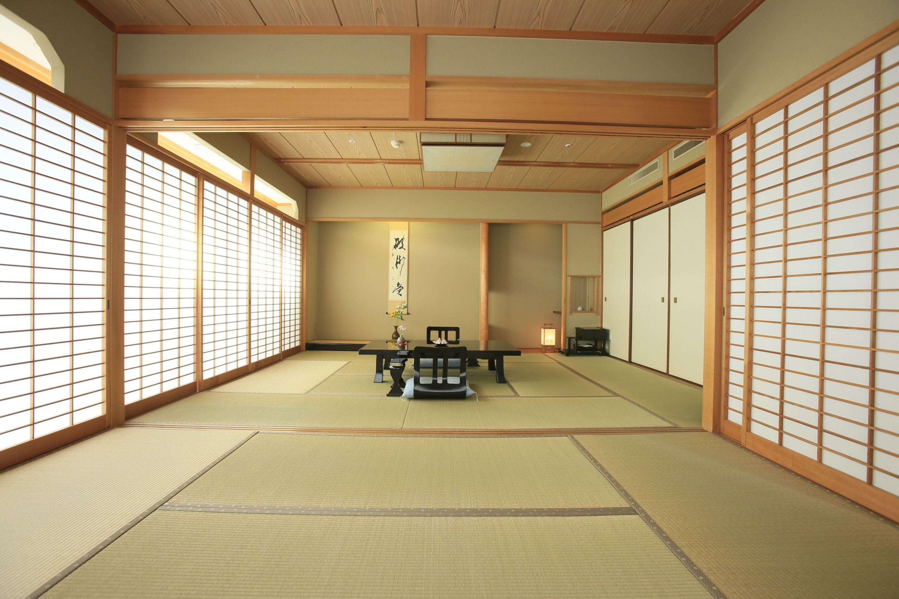 Una habitación japonesa tradicional con suelo de tatami, una mesa baja con una silla, puertas correderas y un divisor shoji.
