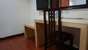 A wooden desk with a chair, a television mounted above it, and a power outlet on the wall. - Phounsiri Hotel (Ban Donnoun)