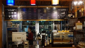 A coffee shop with a menu board displaying various coffee drinks and prices. - Phounsiri Hotel (Ban Donnoun)