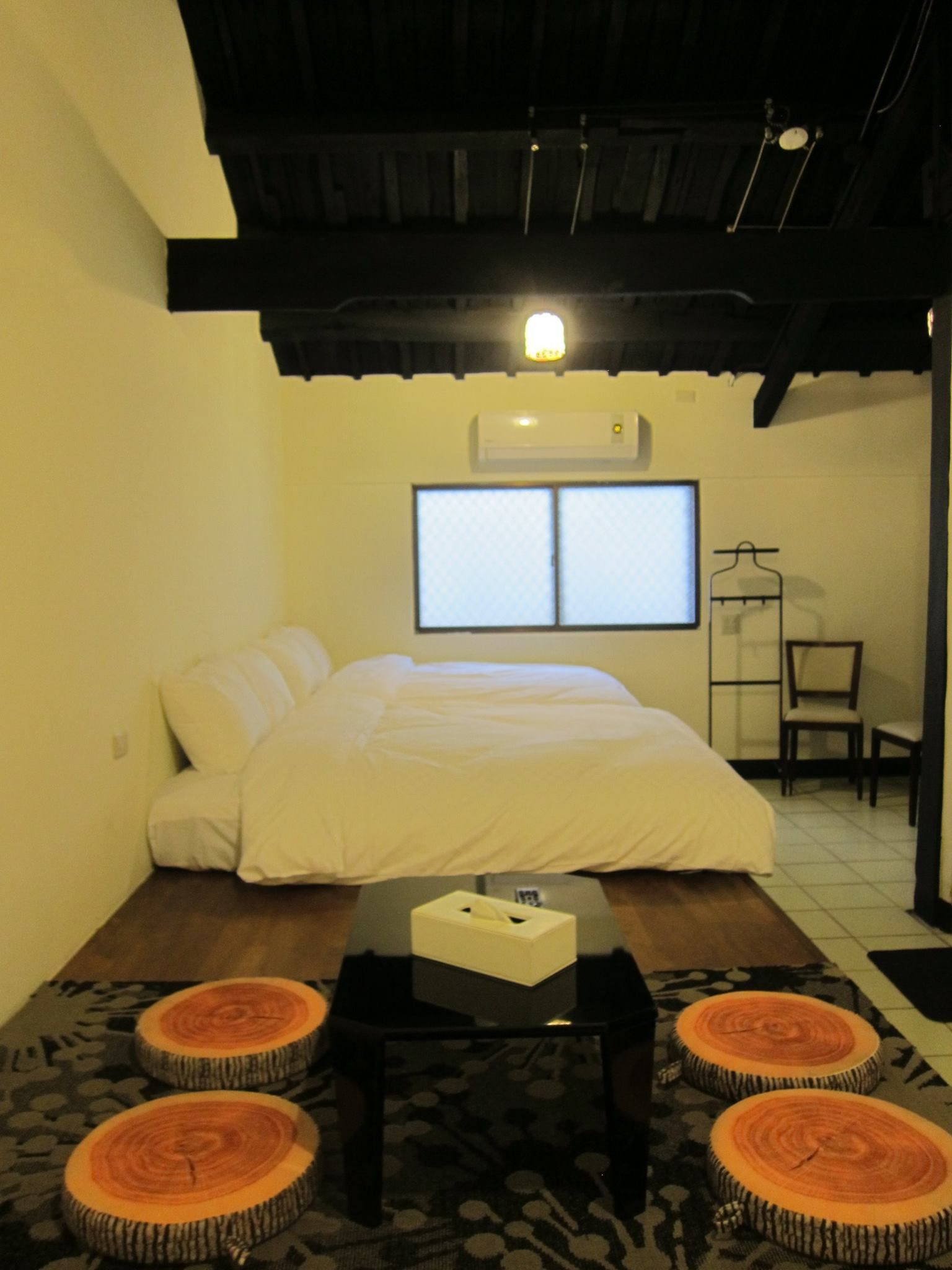A bedroom with a bed, a bedside table, a chair, and a window.
