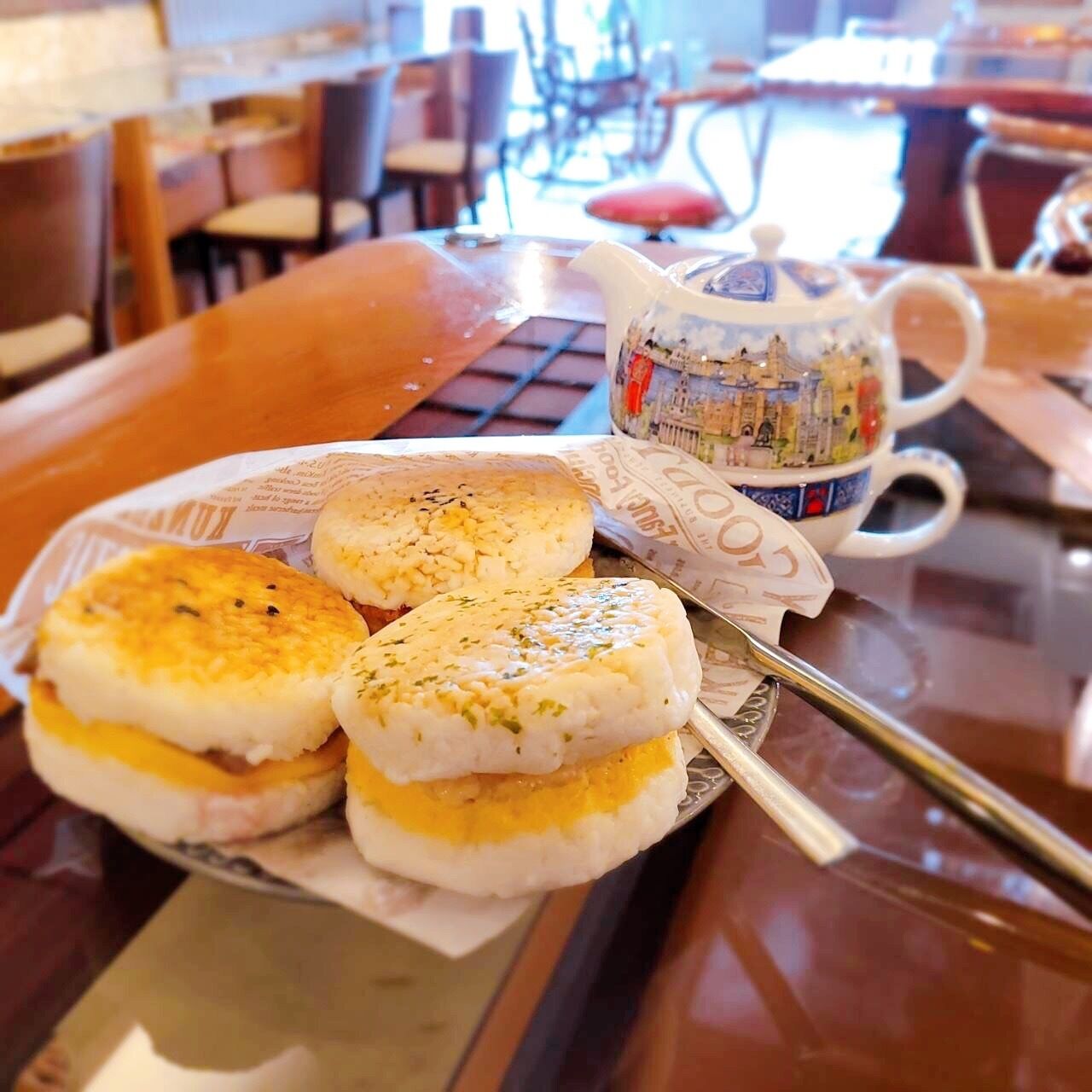 A table with a plate of food, a teapot, and a cup.