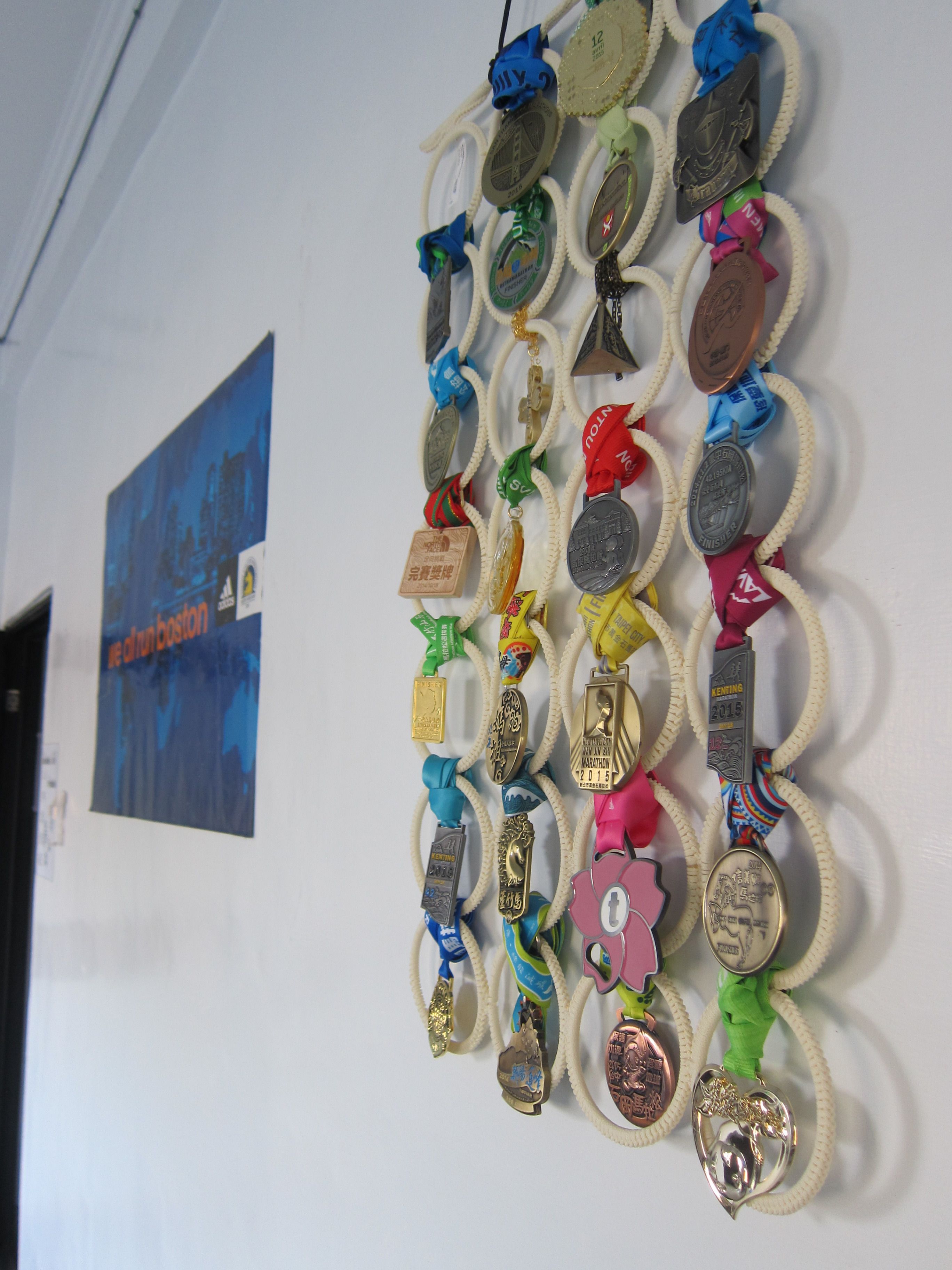 A wall with a collection of medals and ribbons, some with text and others with symbols.