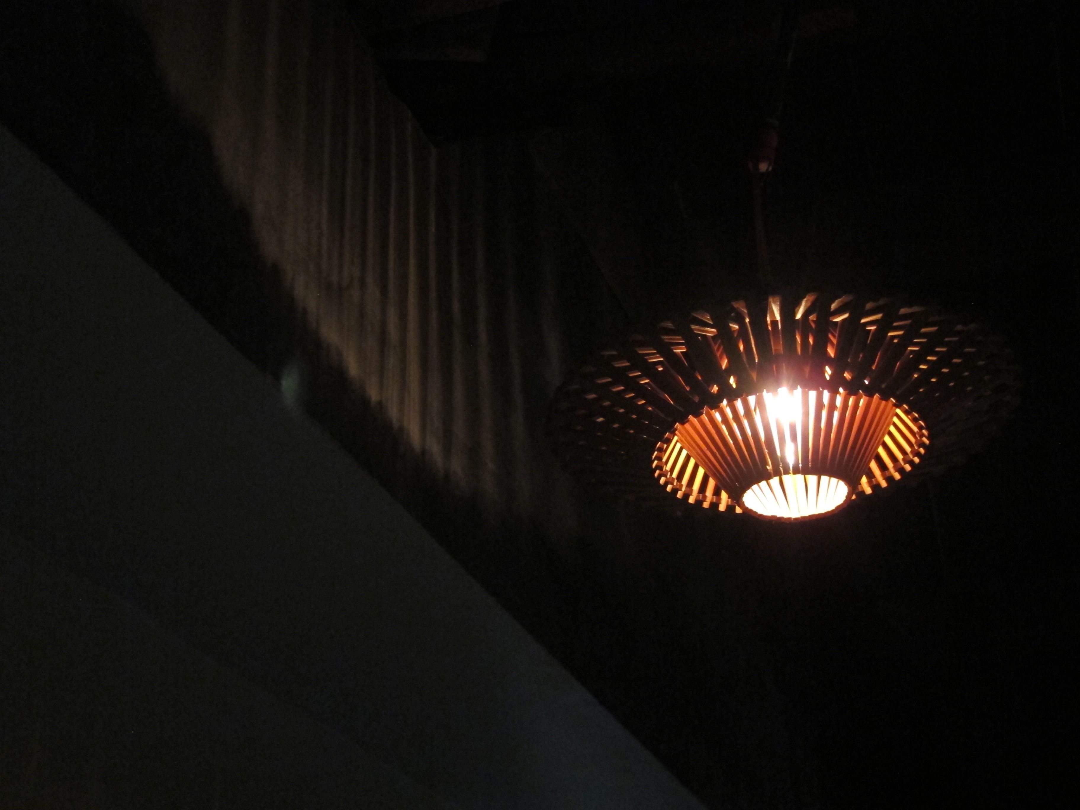 A hanging light fixture with a circular design and vertical slats.