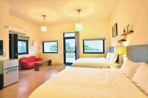 Habitación de hotel con dos camas, una silla roja, una mesita, un refrigerador y una ventana con vistas.