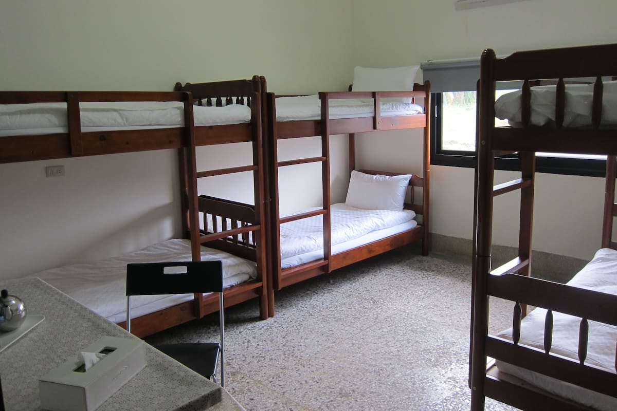 A bunk bed room with a small desk and a window.