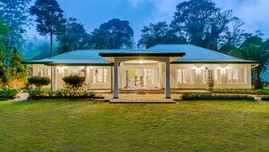 A two-story house with a covered porch, surrounded by lush greenery and trees. - Strathdon by Zinc Journeys (Ginigathena)