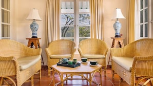 A room with wicker furniture, two lamps, a table with tea set, and a window with curtains. - Strathdon by Zinc Journeys (Ginigathena)