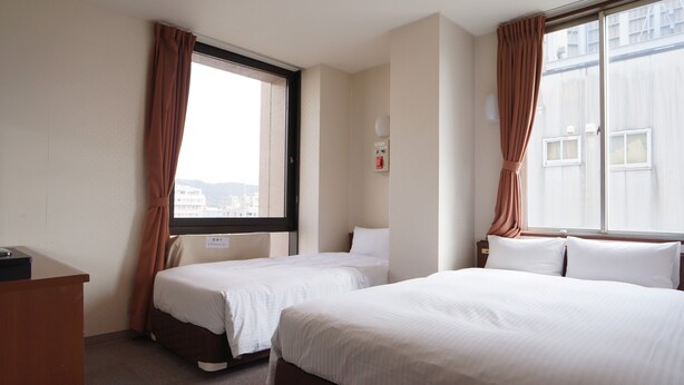 A hotel room with two beds, a desk, and a window with curtains. - Kochi Green Hotel Harimayabashi (Kochi)