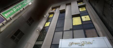 A hotel with a modern facade, large windows, and a prominent sign reading "Green Hotel".