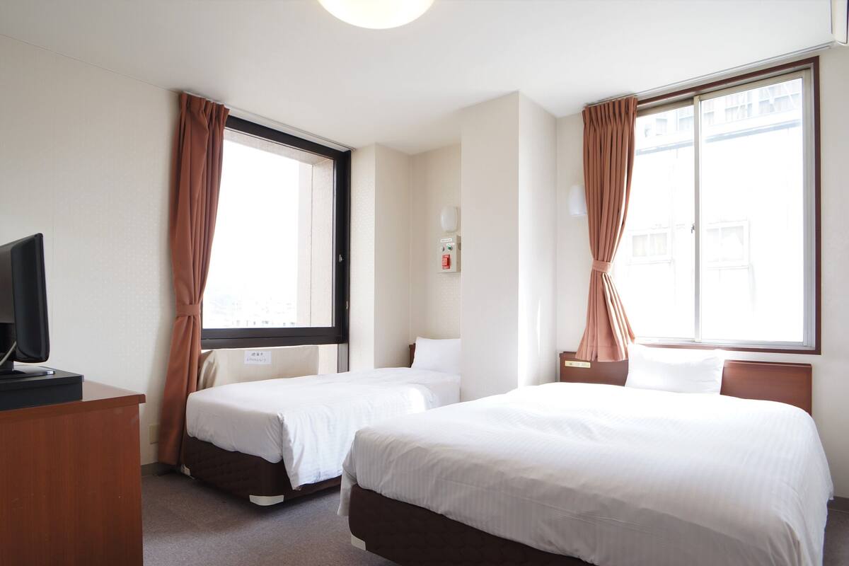 Habitación de hotel con dos camas, un escritorio y un televisor.