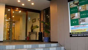 A hotel entrance with a staircase leading up to the door, a potted plant, and a signboard with hotel information. - Kochi Green Hotel Harimayabashi (Kochi)