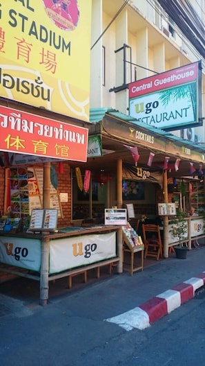A street view with a restaurant named 'ugo' and a sign for 'Central Guesthouse'. - Central Guesthouse (Chiang Mai)