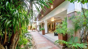 A pathway lined with plants and a brick border, leading to a building with a wooden ceiling and indoor plants. - Sur Beach Resort (Boracay Island)