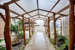 A covered walkway with a wooden floor, flanked by potted plants and a sandy path. - Sur Beach Resort (Boracay Island)