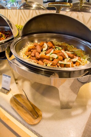 A buffet with various dishes including sausages, shredded vegetables, and a wooden serving tray. - Sur Beach Resort (Boracay Island)