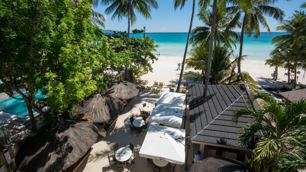 A beachside resort with thatched umbrellas, lounge chairs, and a pool. - Sur Beach Resort (Boracay Island)