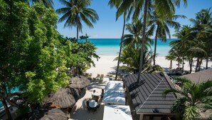 A beachside resort with thatched umbrellas, lounge chairs, and a view of the ocean. - Sur Beach Resort (Boracay Island)
