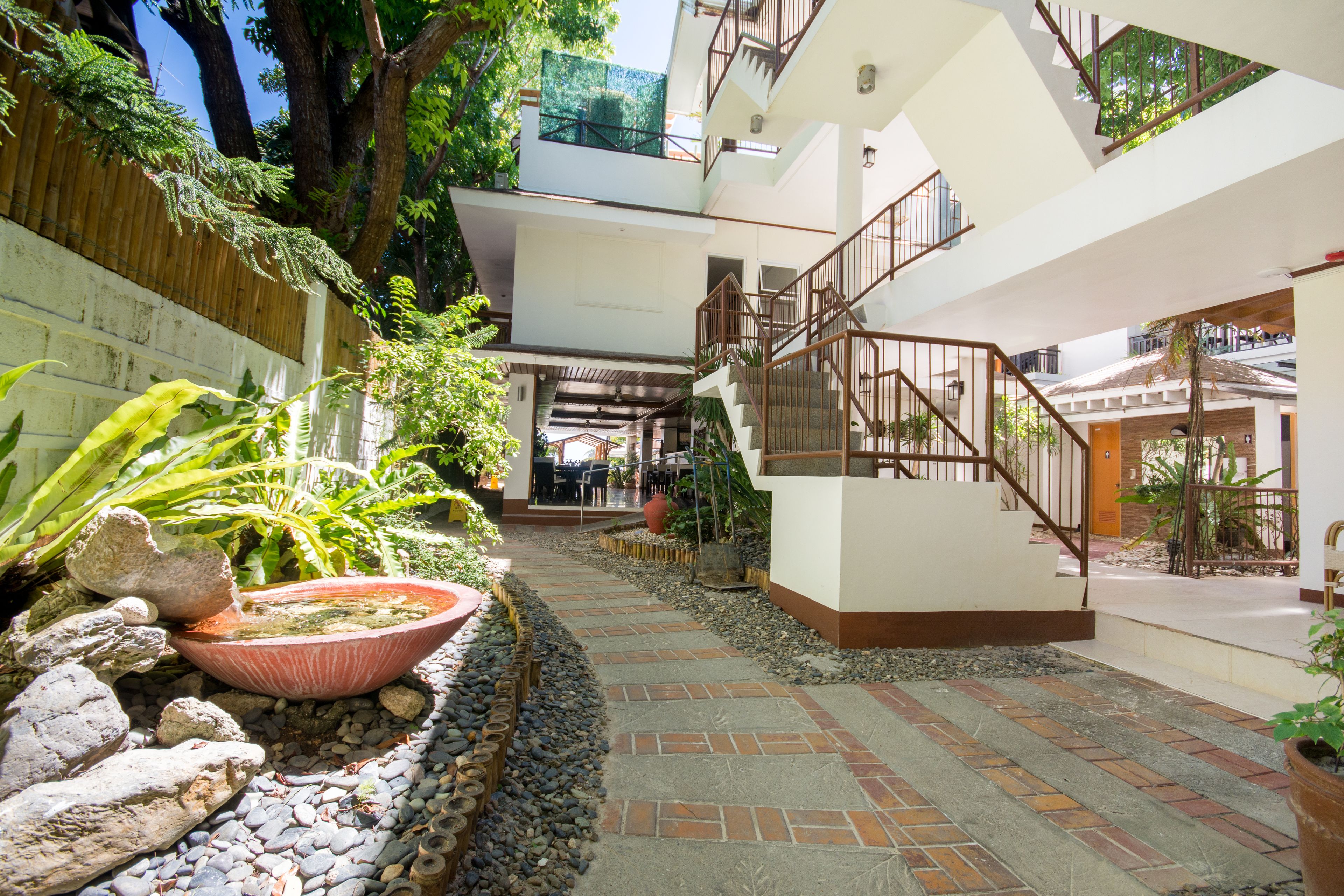 A multi-level building with a central courtyard, stone pathways, and a variety of plants.