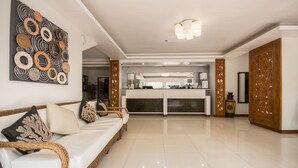 A spacious living area with a modern sofa, a decorative wall piece, and a bright chandelier. - Sur Beach Resort (Boracay Island)