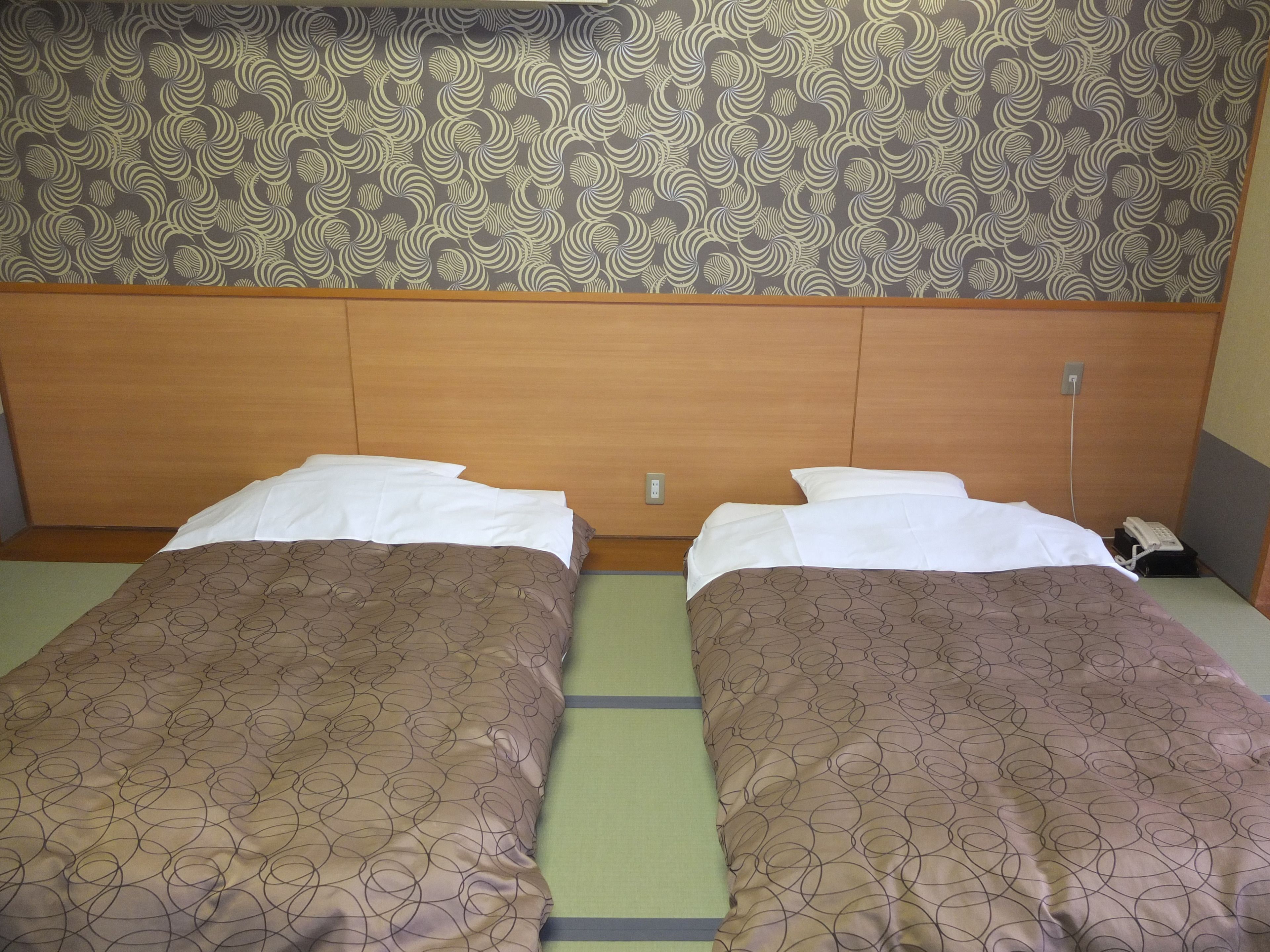Una cama doble con una colcha estampada, un cabecero de madera y un papel tapiz decorado.