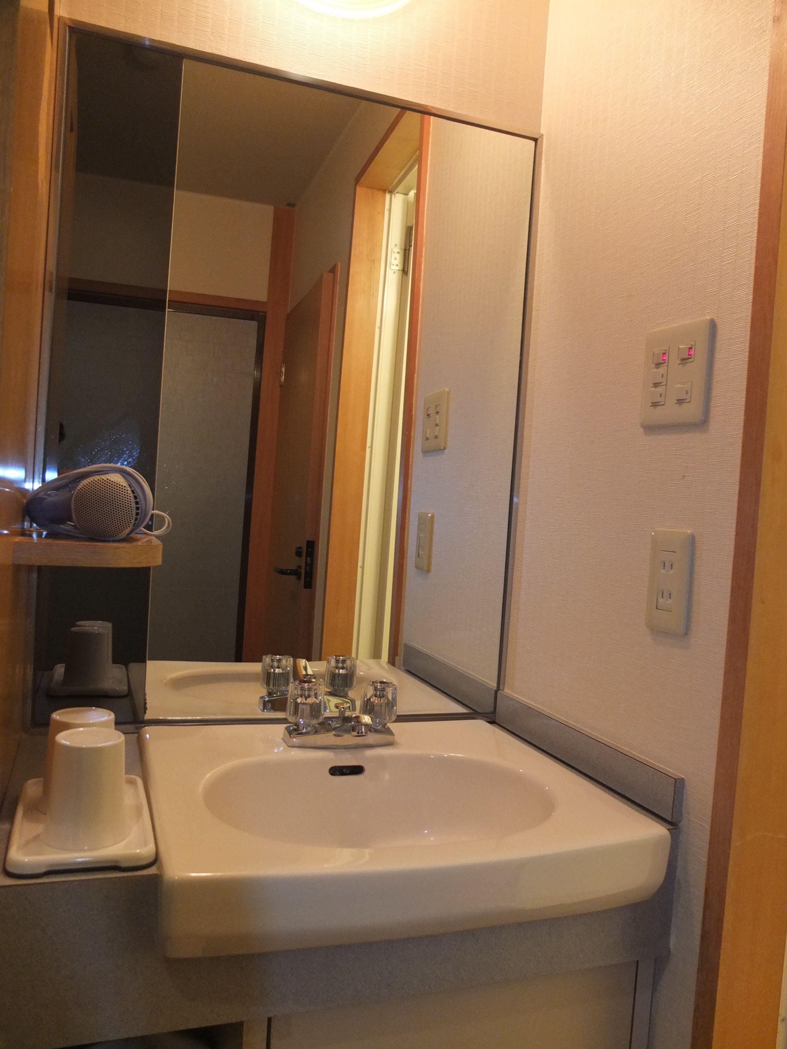 Un baño con lavamanos, espejo y perchero para toallas.