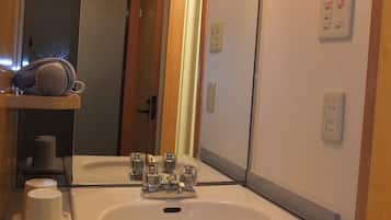 Un baño con lavamanos, espejo y perchero para toallas.
