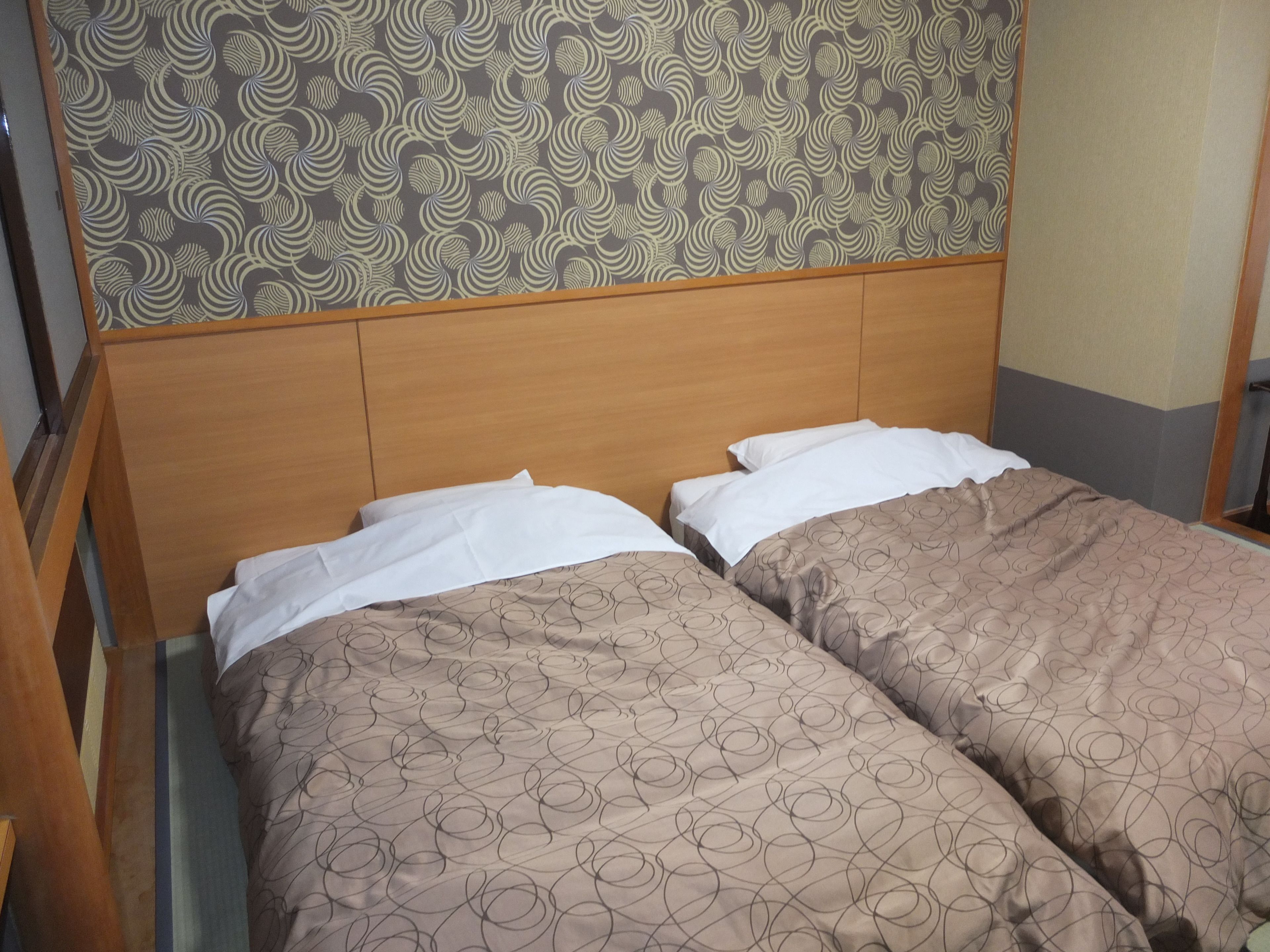 A double bed with a wooden headboard and patterned bedding.