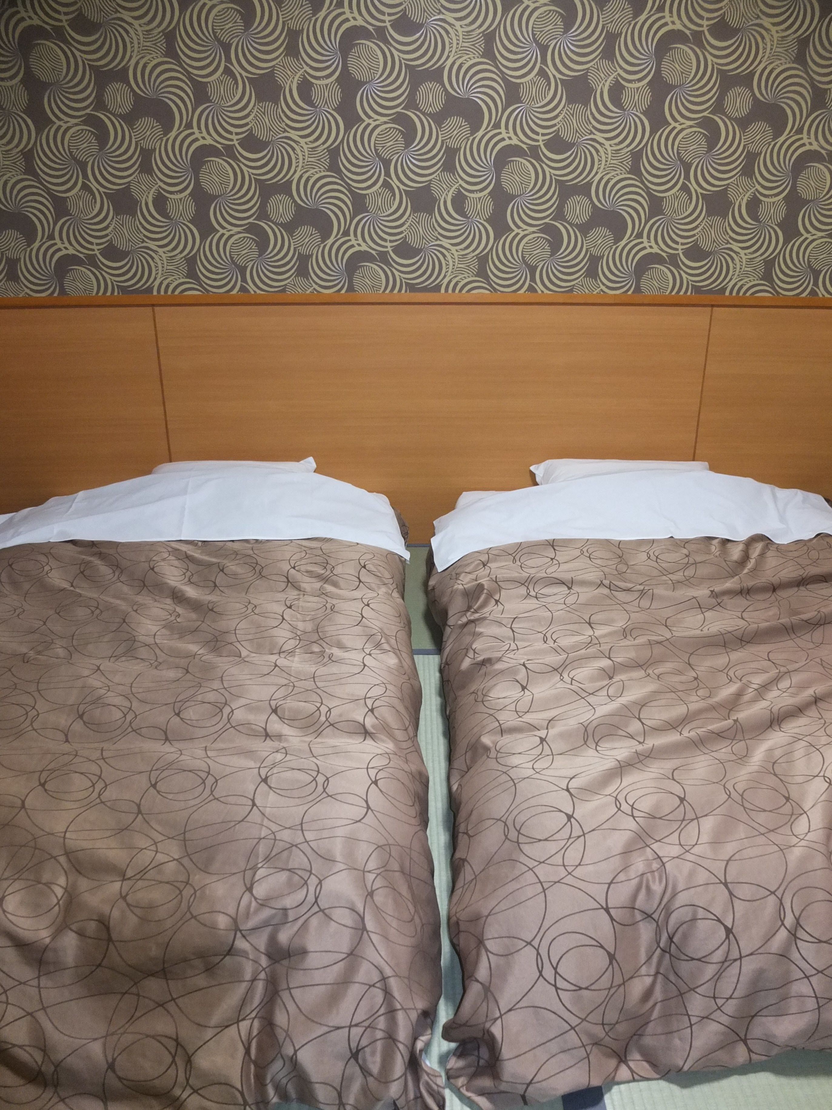 A bed with a headboard, two pillows, and a patterned bedspread.