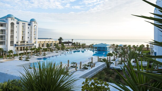 A resort with a large pool, palm trees, and a view of the ocean. - Hotel Concorde Green Park Palace (Port El Kantaoui)