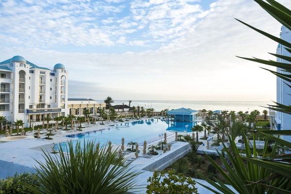 Una piscina techada, una piscina al aire libre, sombrillas