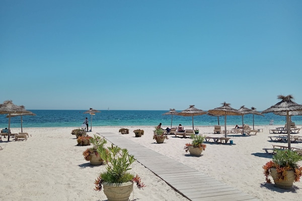 On the beach, white sand, sun-loungers, beach umbrellas