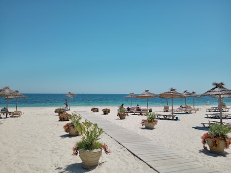 On the beach, white sand, sun loungers, beach umbrellas
