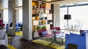 A modern interior with a central bookshelf, seating area, and a table with a laptop.
