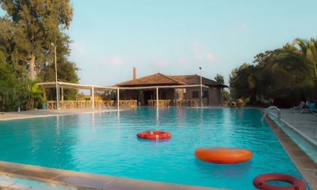 Una piscina al aire libre, sillones reclinables de piscina