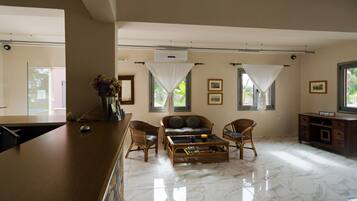 A spacious living room with a sofa, two chairs, a coffee table, and a TV stand.