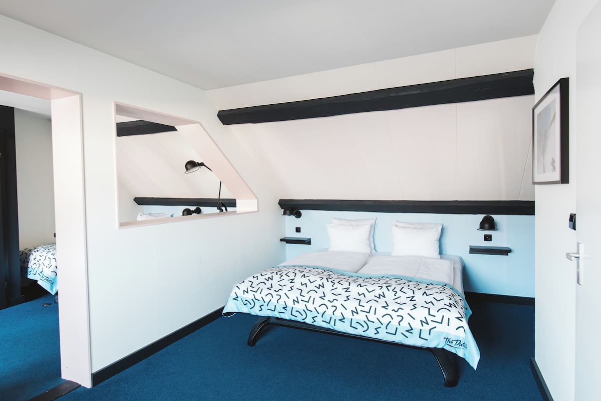 Ein Schlafzimmer mit Bett, Nachttisch, Spiegel und Ablagefläche.