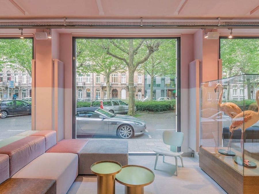 A modern interior with seating areas, large windows, and a view of the street.