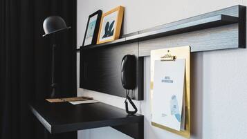 Un escritorio con un teléfono, un bloc de notas y marcos con fotografías en una repisa de pared.