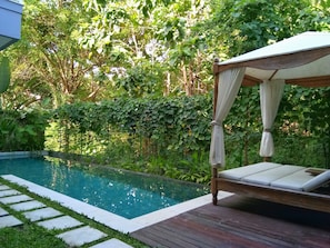A wooden deck with a pool and a canopy bed.