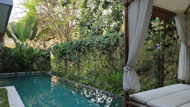 Ein klares Schwimmbecken mit Holzterrasse und Sonnensegel.