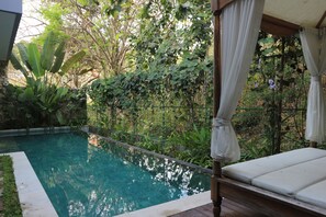 Ein klares Schwimmbecken mit Holzterrasse und Sonnensegel.