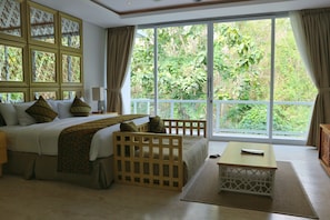 A bedroom with a large window, a bed, a nightstand, a wooden crib, and a small table.