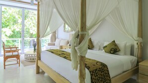 Ein Himmelbett mit weißen Vorhängen, einem Holzkopfende und einer grün gemusterten Bettdecke.