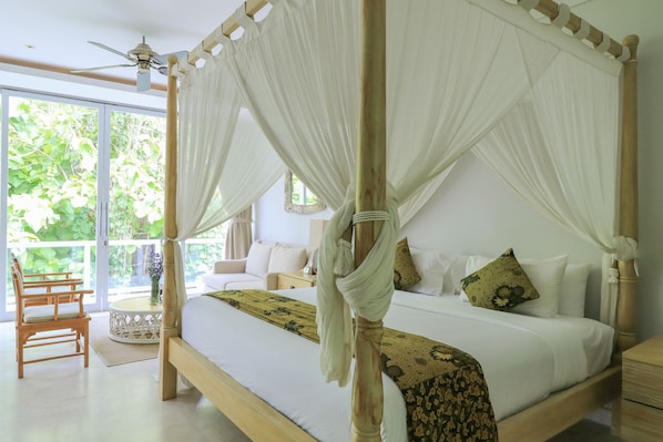 A four-poster bed with white drapes, a wooden headboard, and a green patterned bedspread.