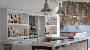 Zona de bar con estantes llenos de botellas de licor, luces colgantes y una barra.
