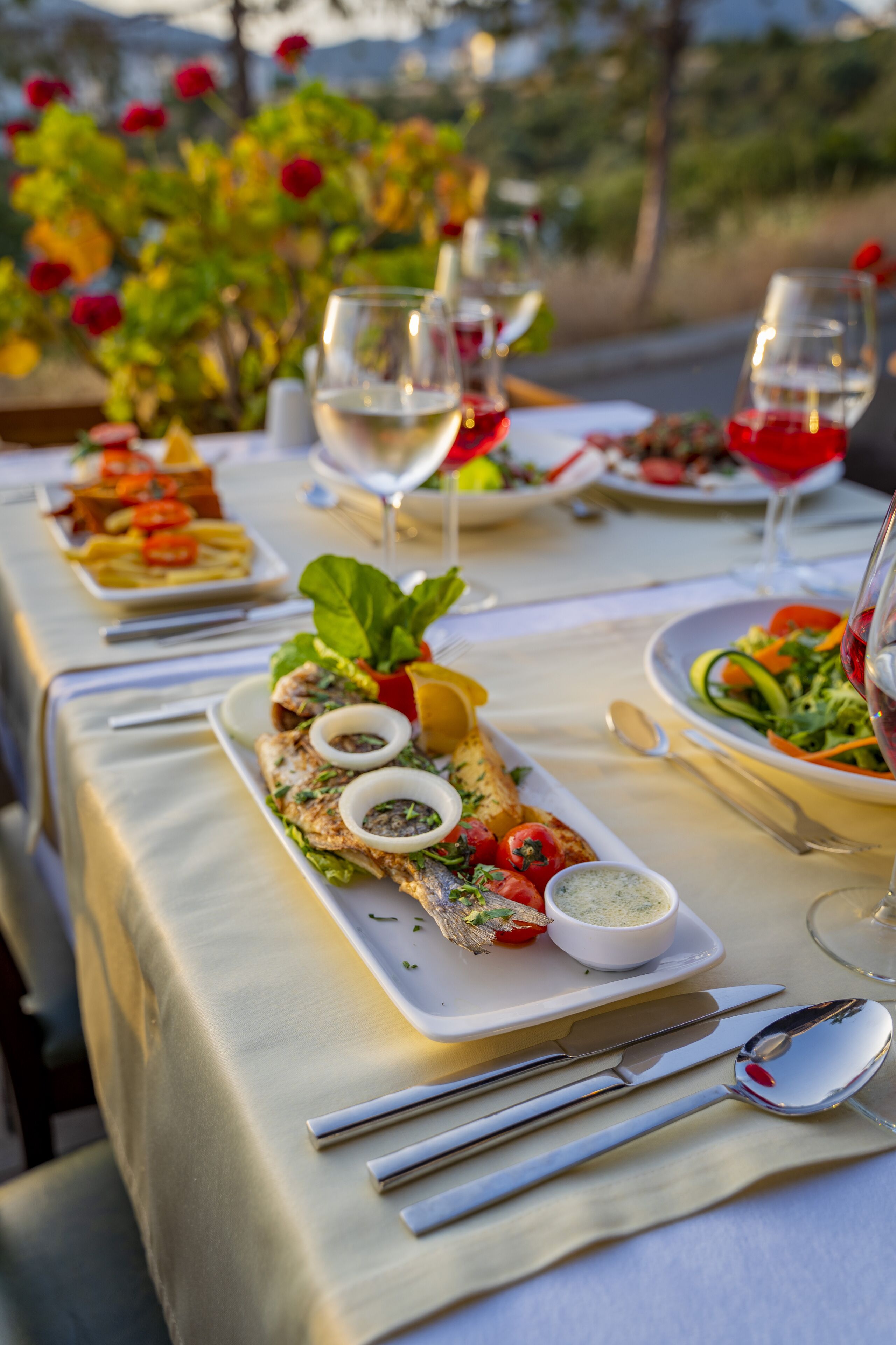 Une table dressée avec des assiettes remplies de nourriture, des verres de vin et des couverts.