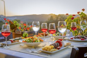 Ein gedeckter Tisch mit verschiedenen Speisen und Weingläsern, mit Blick auf eine reizvolle Landschaft.