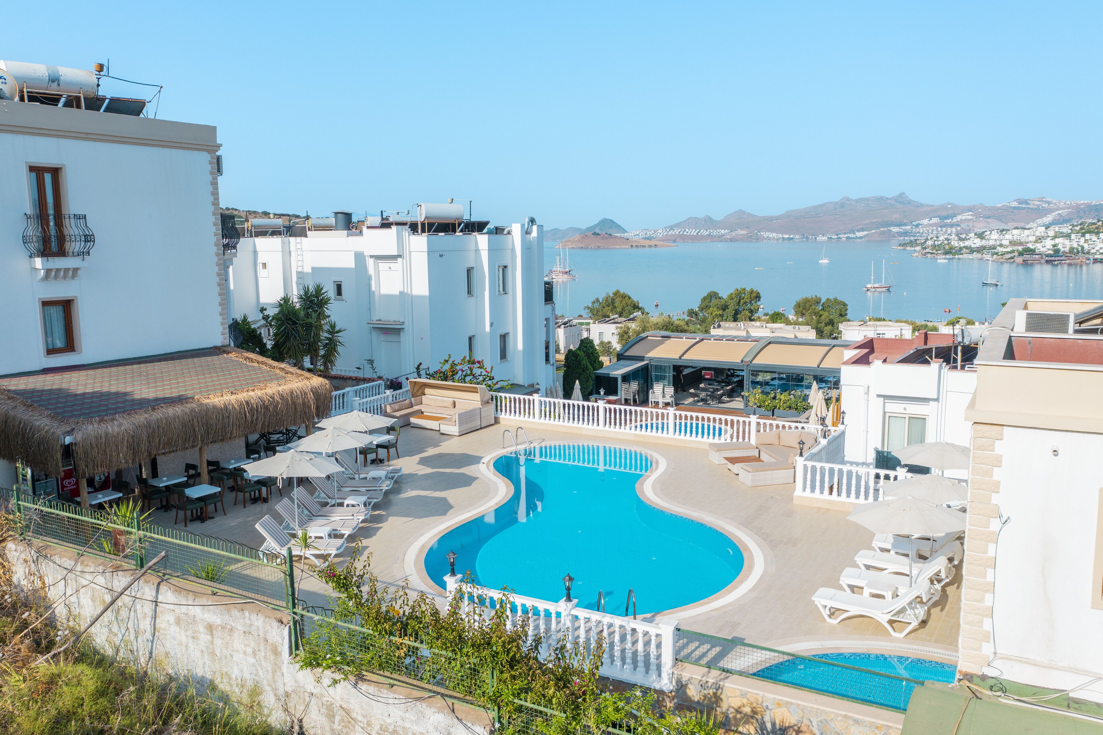 A resort with a swimming pool, lounge chairs, and a view of the sea.