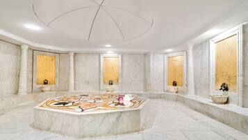 Bathroom features a central bathtub, high ceiling, and large windows with wicker blinds.